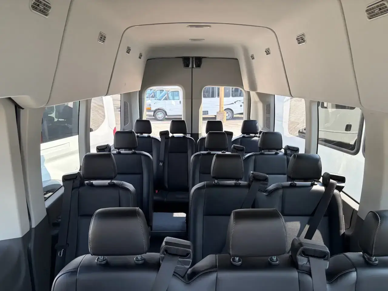 Interior of a 15 passenger Ford Transit van conversion with individual seats, headrests, three point shoulder harness belts, and a center aisle